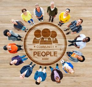 Diverse group of people standing around a circular image with the words 'people' and 'community' looking up at the camera